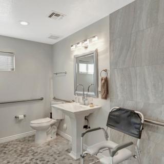 A modern and accessible bathroom with a sink, toilet, and grab bars.