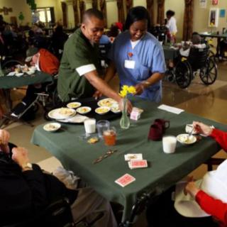 Caregivers assist elderly residents during a meal at a nursing home.