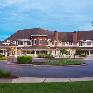 A large residential building with a circular driveway and well-maintained landscaping at dusk.