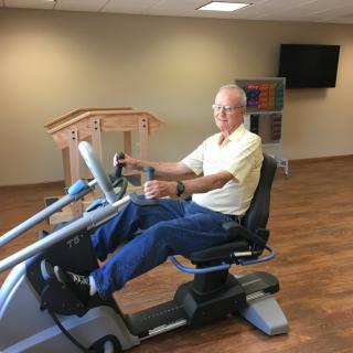 A senior person exercising on a recumbent bike indoors.