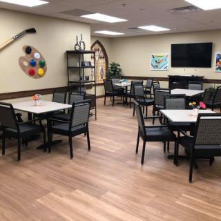 A spacious art room with tables and chairs, featuring artistic decorations and a TV.