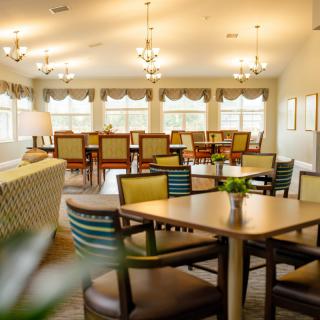 A well-lit dining area with tables, chairs, and large windows creating a cozy atmosphere.