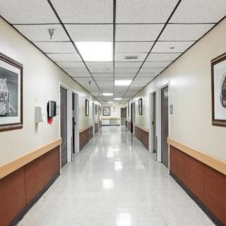 A clean and well-lit hospital corridor with framed artwork on the walls.