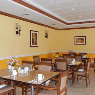 An empty restaurant dining area with neatly arranged tables and chairs, featuring wall decorations and a warm color scheme.