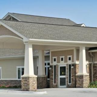 A commercial building with a prominent entrance featuring columns and a sloped roof.