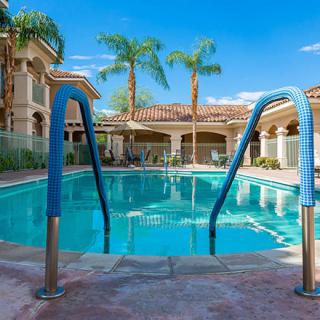 A serene outdoor swimming pool surrounded by palm trees and resort-style buildings, ideal for a relaxing vacation.