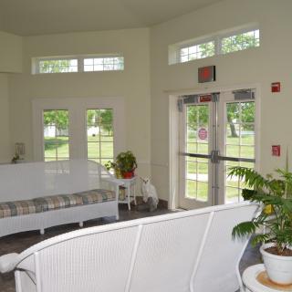 A bright and airy lobby with white furniture, large windows, and indoor plants.