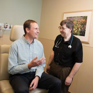 A doctor and patient engage in a friendly conversation during a medical consultation.