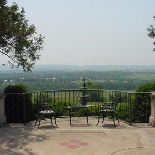 A serene outdoor balcony with two benches overlooks a vast landscape under a clear sky.