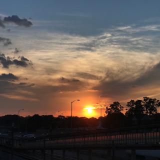 A beautiful sunset casts a warm glow over the horizon, with clouds adding depth to the evening sky.