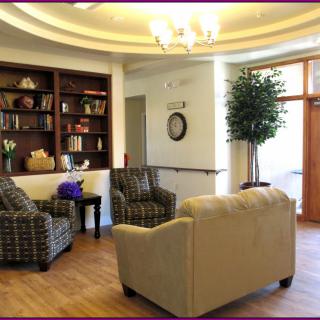 A cozy seating area featuring a bookshelf, comfortable chairs, and a sofa with soft lighting.