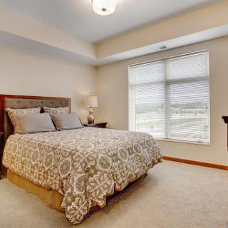A cozy modern bedroom featuring a large bed, decorative pillows, and a window allowing natural light.