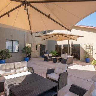 A sunny patio with comfortable seating and large umbrellas providing shade.