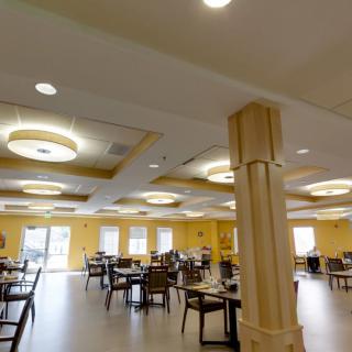 A spacious dining room with tables and chairs arranged neatly under stylish ceiling lights.