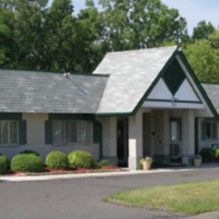 A small residential building with green shutters and well-maintained landscaping.