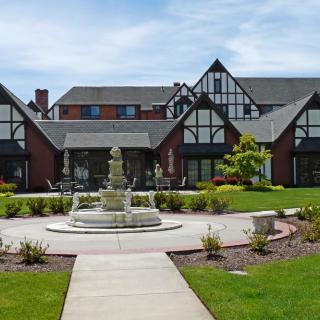A Tudor-style building with a central fountain and landscaped gardens.