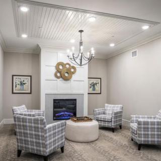 A modern living room featuring a stylish fireplace, four plaid armchairs, and a sleek chandelier.