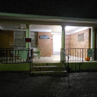 A well-lit entrance of a building at night, showcasing the steps and porch.