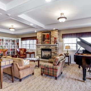 A cozy living room featuring a grand piano, fireplace, and bookshelves.