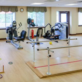 A spacious exercise room equipped with various fitness machines and rehabilitation tools.