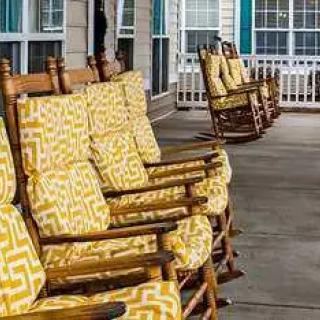 Wooden rocking chairs with patterned cushions lined up on a porch.