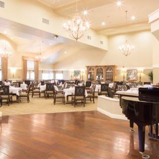 An elegant dining area with a grand piano and chandeliers.