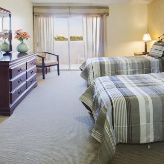 A cozy bedroom with twin beds, featuring striped bedspreads and elegant furniture.