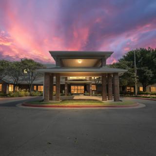 A building entrance illuminated during sunset with a dramatic sky overhead.