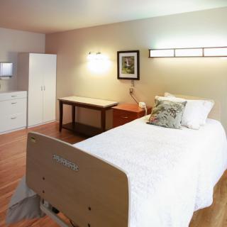 A well-organized hospital room with a single bed and simple furnishings.