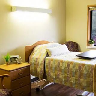A cozy hospital room with a single bed, nightstand, and window.