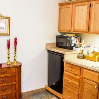 A small kitchen area with wooden cabinets, a microwave, and a mini fridge.