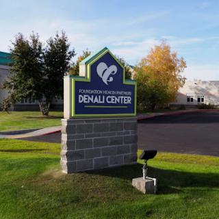 The sign for the Denali Center, a healthcare facility surrounded by greenery.