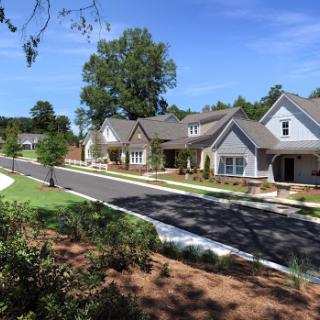 A peaceful suburban neighborhood showcasing well-maintained homes and a clear blue sky.