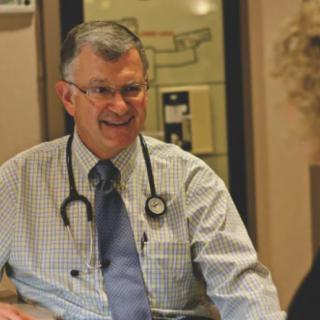 A doctor with a stethoscope smiles during a consultation.