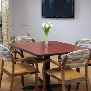 A cozy dining area with a wooden table, chairs, and a vase of flowers.