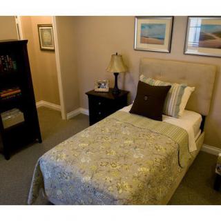 A cozy bedroom with a single bed, nightstand, and decorative artwork.