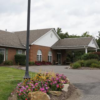 A brick building with a well-maintained garden and driveway.