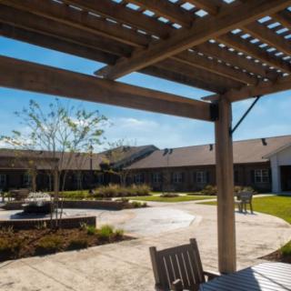 A sunny courtyard with a pergola, outdoor seating, and well-maintained landscaping.