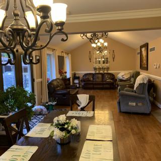 A cozy living room and dining area featuring chandeliers, comfortable seating, and elegant decor.
