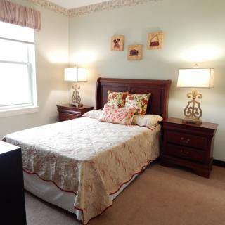 A cozy bedroom interior with a neatly made bed, two nightstands, and decorative lamps.