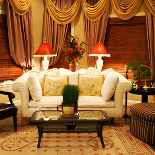 A cozy living room with elegant decor, featuring a white sofa, red lamps, and ornate curtains.