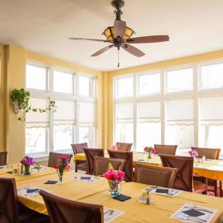 A bright dining room with neatly arranged tables, chairs, and decorative flowers.