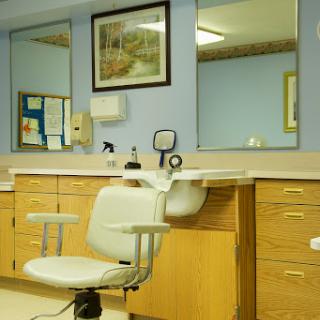 A view of a dental office featuring a comfortable dental chair, cabinets for equipment, and mirrors reflecting a calm environment.