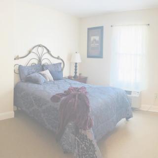 A cozy bedroom with a neatly made bed and soft lighting.