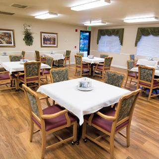 A well-arranged dining room with tables and chairs, featuring tablecloths and decorative elements.