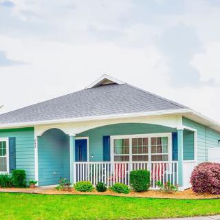 A charming blue suburban house with a white porch and well-maintained yard.