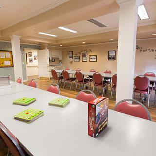 An empty community center meeting room with tables, chairs, and a few books on display.