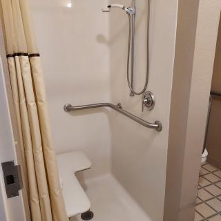 An accessible bathroom with a shower featuring grab bars and a seat.