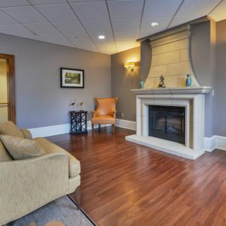 A cozy living room featuring a fireplace, sofa, and wooden flooring.