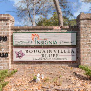 A sign for Bougainvillea Bluff apartment community, featuring a brick wall with detailed text.